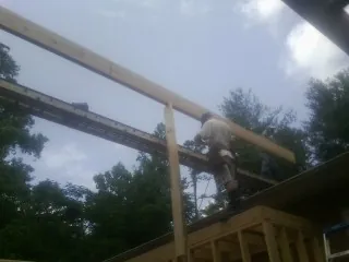 Carpenter setting a ridge beam over a new addition frame — Ice Dam Removal by Roofing Brothers in Big Rock