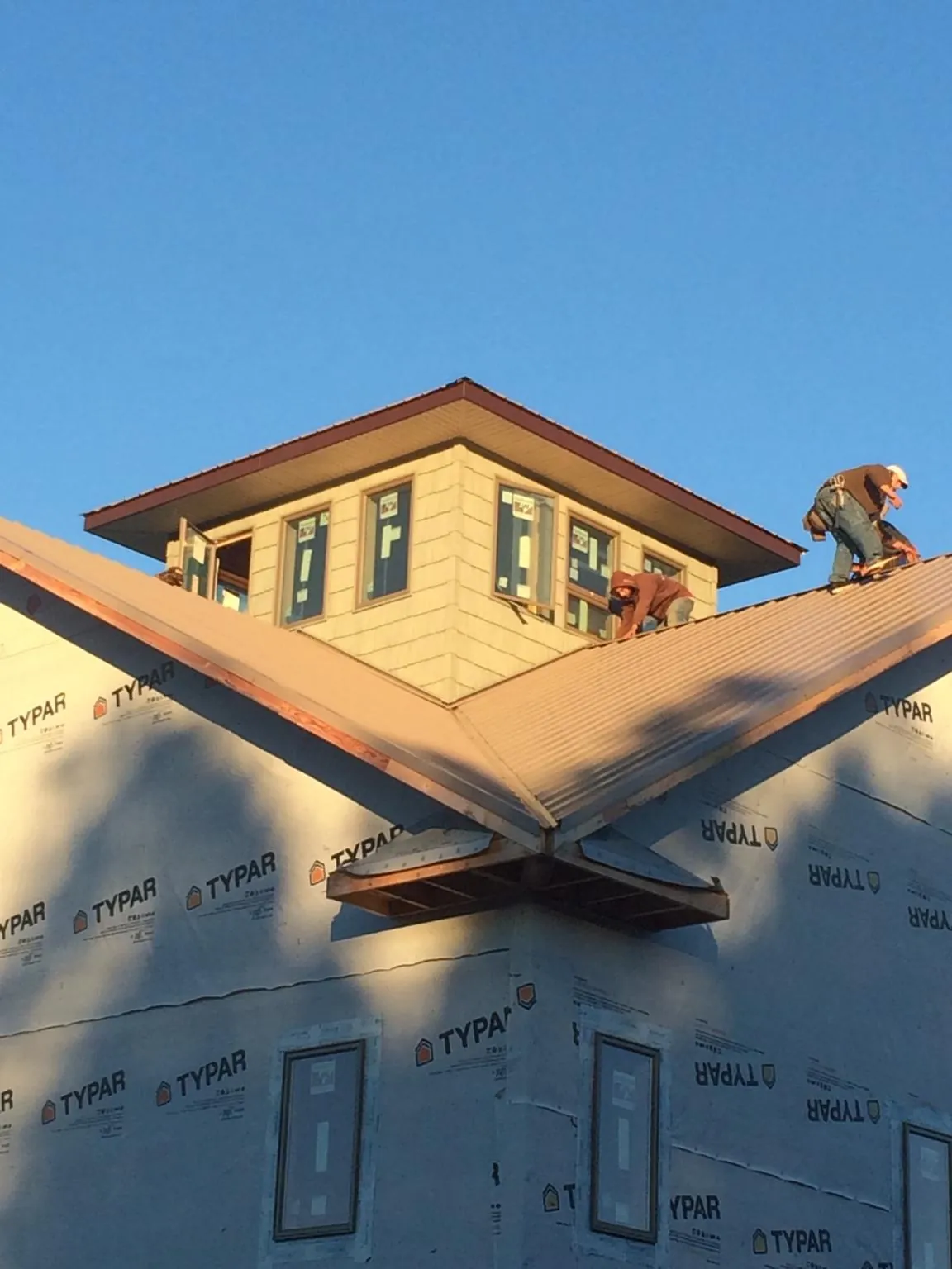 Roofers working around a rooftop cupola on a new metal roof at sunset — Roof Waterproofing in Big Rock by Roofing Brothers